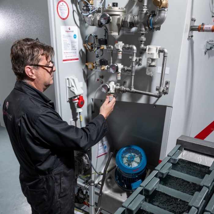 Vapormatt engineer maintaining a Vapormatt Cougar + automatic wet blasting machine