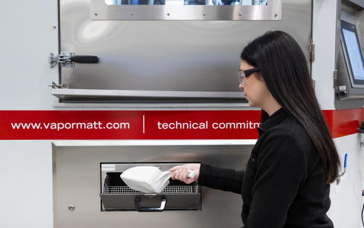 A Vapormatt Sabre automatic wet blasting machine being loaded with blast media