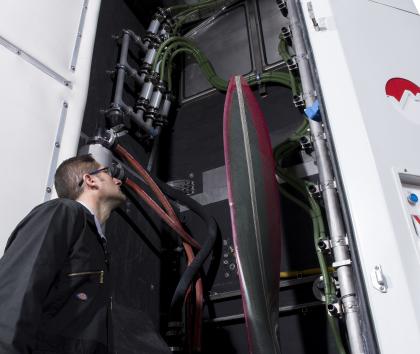Photo of an operator looking at a propeller blade mounted in a Vapormatt Leopard Cub automatic wet blasting machine