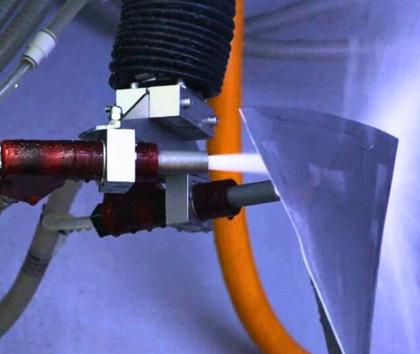 A jet engine fan blade being wet blasted