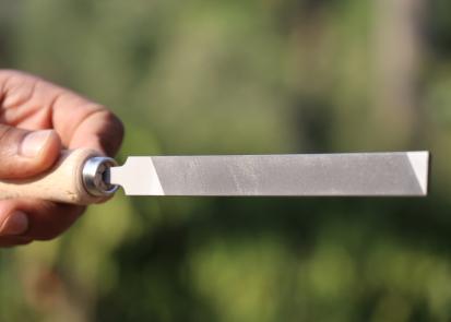 Flat steel file with wooden handle being held in the hand